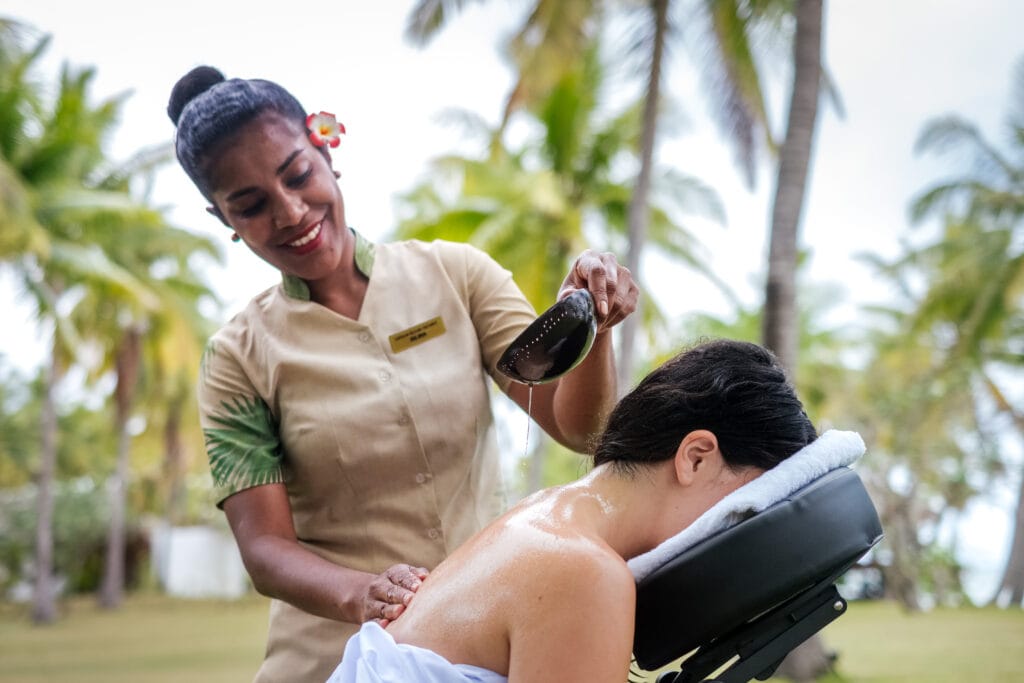 Woman receiving a neck and shoulder massage outdoors.