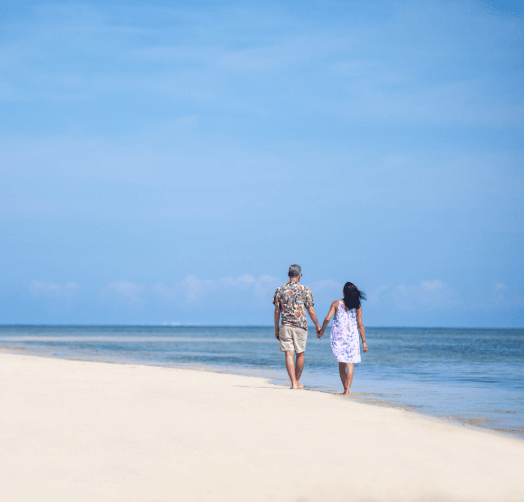 Couple walking on the white sandy beach at Lomani Island Resort