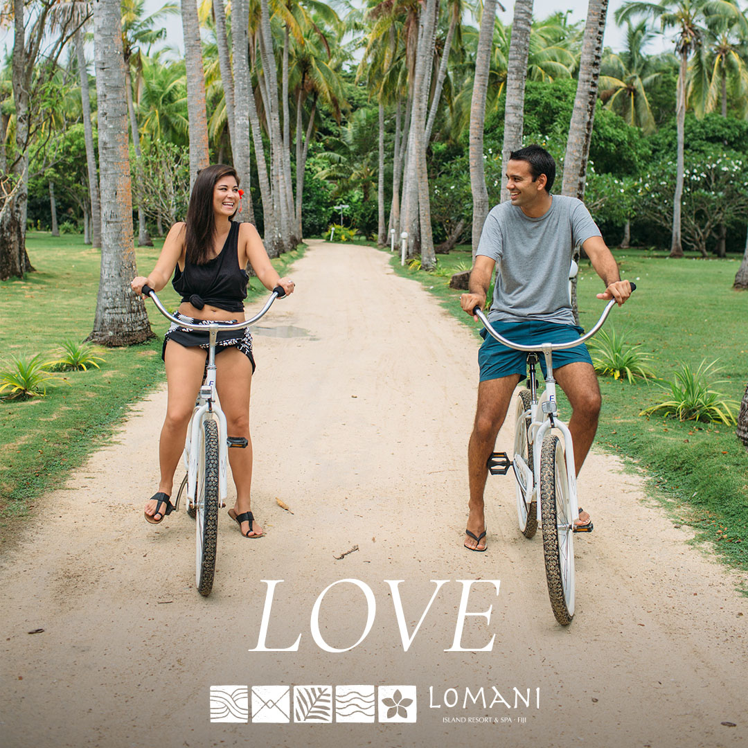 couple ride bikes looking lovingly at each other
