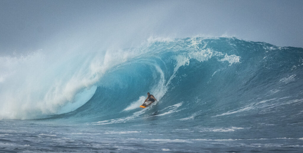 Surfer riding a large turquoise wave.