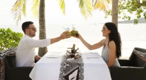 A couple enjoying a drink during a private sunset dinner at Lomani Island Resort & Spa.