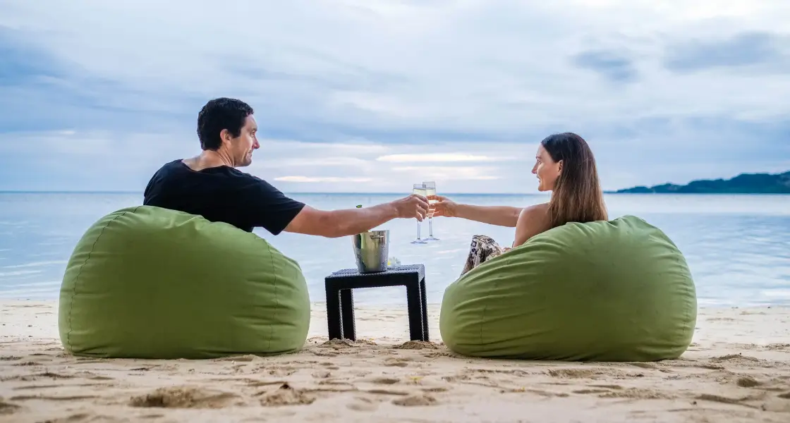 A couple enjoying a drink on beach bean bags in Fiji