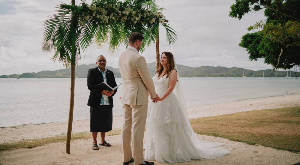 Bride and groom stand at the alter together holding hands with their wedding celebrant