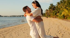 Couple embracing on the beach with the sunset behind them